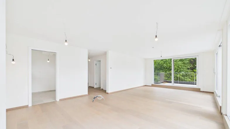 Helles, geräumiges Wohnzimmer mit Parkettboden und großen Fensterfronten, die Zugang zum Balkon bieten.