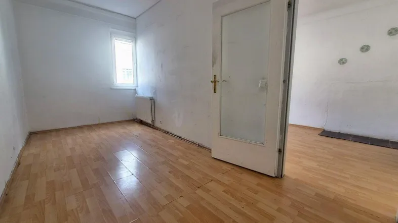 Leerer Raum mit Holzboden und Fenster, bereit zur individuellen Gestaltung und Nutzung.