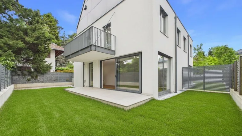 Moderne Doppelhaushälfte mit gepflegtem Rasen und einer Terrasse, ideal für entspannte Stunden im Freien.