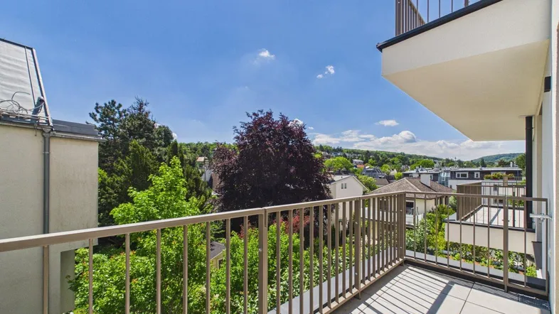 Geräumiger Balkon mit Fliesenboden und weitem Blick ins Grüne und auf die umliegende Bebauung.