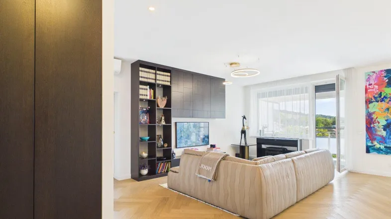 Helles Wohnzimmer mit modernem Sofa, Bücherregal und Blick ins Grüne.