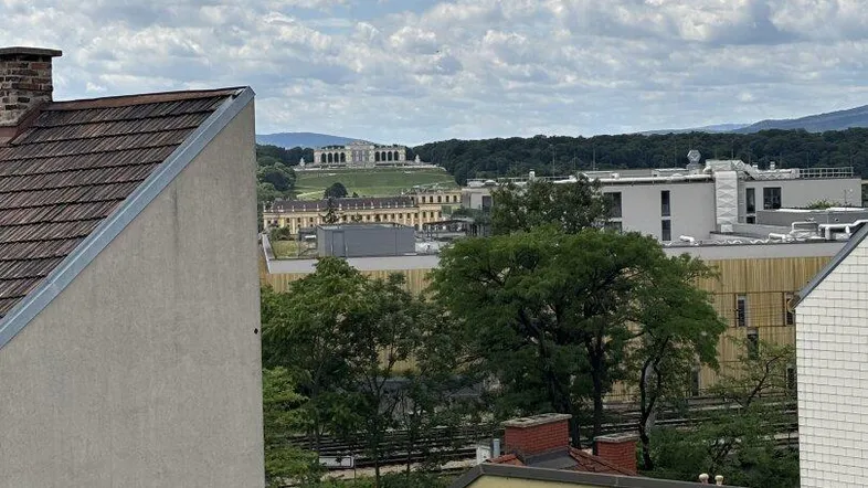 Weitblick über die Stadt und grüne Hügel mit einem historischen Gebäude im Hintergrund.
