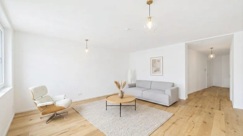 Helles Wohnzimmer mit modernem Sofa, Sessel und Holzboden, ideal für entspannte Stunden.