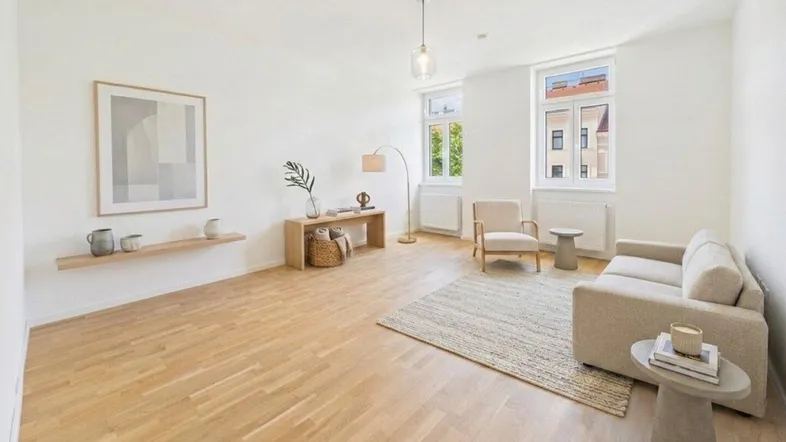 Helles Wohnzimmer mit Parkettboden, modernen Möbeln und Blick ins Grüne durch große Fenster.