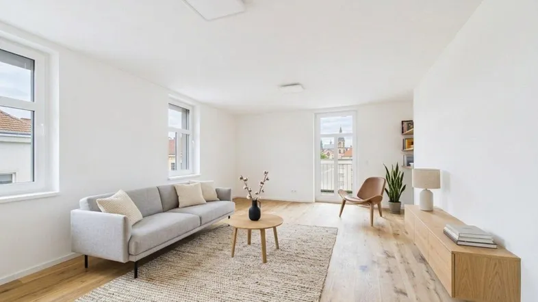 Helles Wohnzimmer mit modernem Sofa, Holzboden und Zugang zu einem französischen Balkon mit Stadtblick.