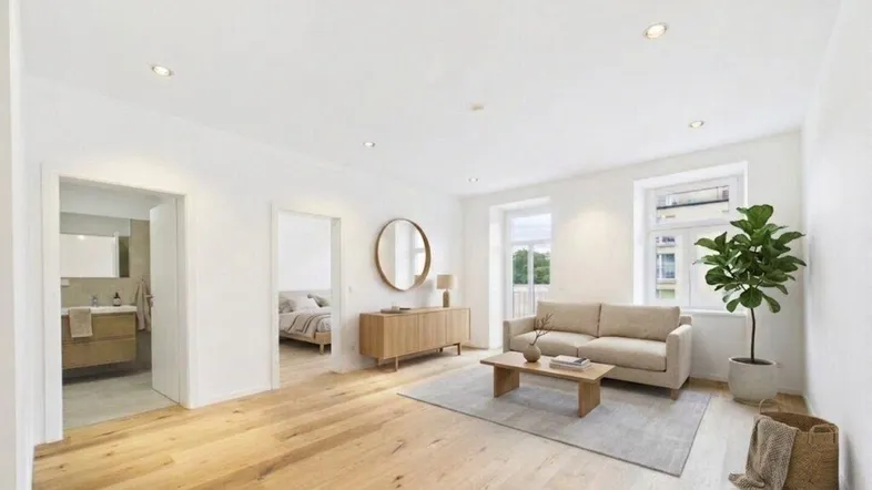 Helles Wohnzimmer mit Holzboden, beigem Sofa und Zugang zu Bad und Schlafzimmer.