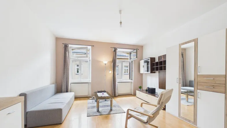 Helles Wohn-Esszimmer mit Parkettboden, beigen Wänden und Blick auf die Straße durch große Fenster.