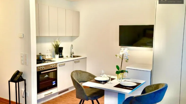 Moderne Küchenzeile mit Essbereich und integriertem Fernseher in hellem Ambiente.