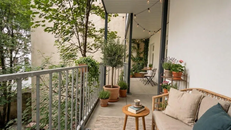 Einladender Balkon mit gemütlichen Möbeln, Pflanzen und stimmungsvoller Lichterkette.