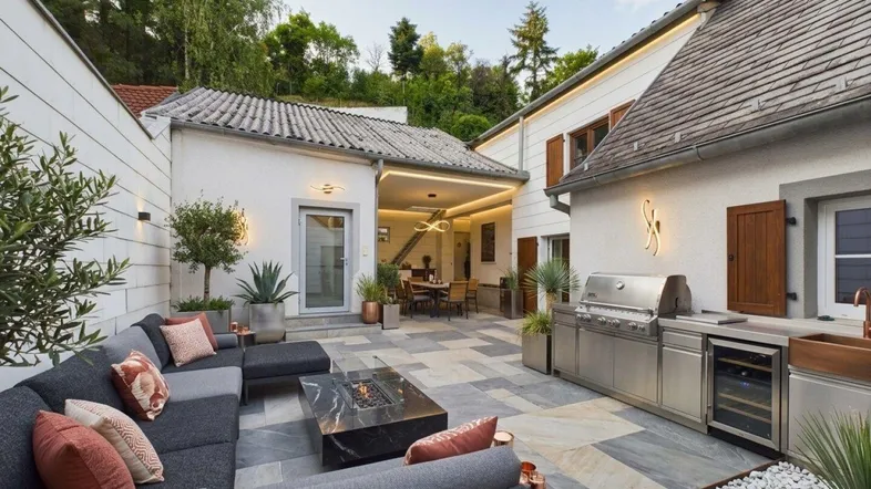 Große moderne Terrasse mit Lounge-Möbeln, Außenküche und überdachtem Essbereich.