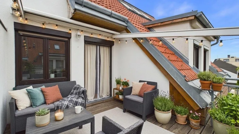 Geräumige Dachterrasse mit gemütlichen Sitzmöbeln, Lichterkette und vielen Pflanzen.