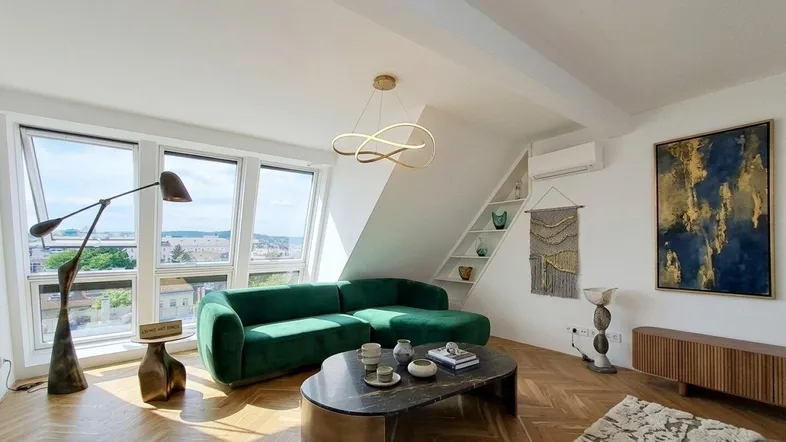 Helles Wohnzimmer mit moderner Einrichtung, grüner Couch und Fischgrätparkett.