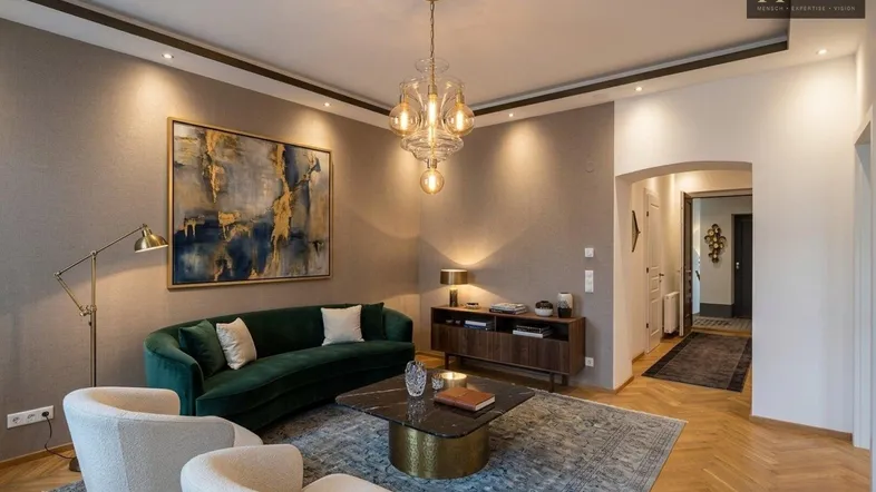 Elegantes Wohnzimmer mit modernem Mobiliar, Fischgrätparkett und stimmungsvoller Beleuchtung.