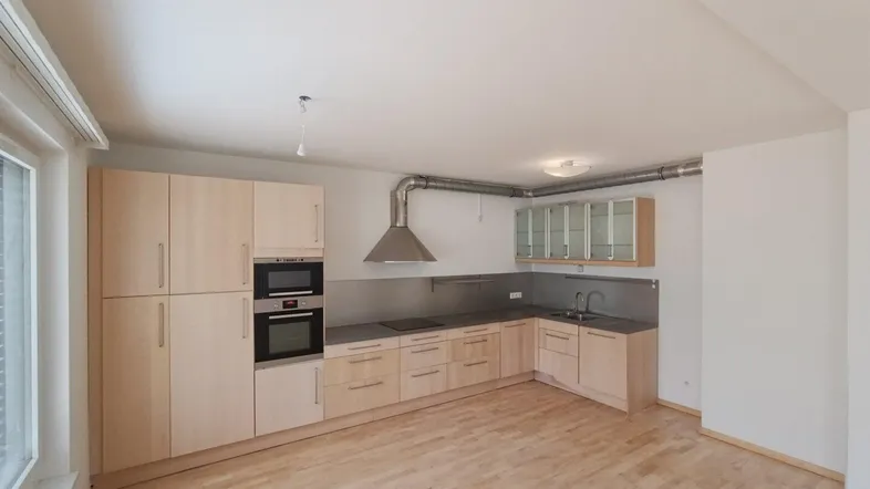 Helle Einbauküche mit Holzfronten, integriertem Backofen und Dunstabzugshaube in offenem Wohnbereich.