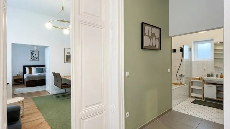 Heller Flur mit grün gestrichener Wand, der zu Schlafzimmer und Badezimmer führt.