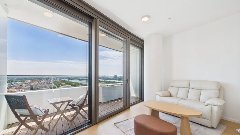 Helles Wohnzimmer mit Holzboden, moderner Einrichtung und Zugang zu einem Balkon mit Weitblick.