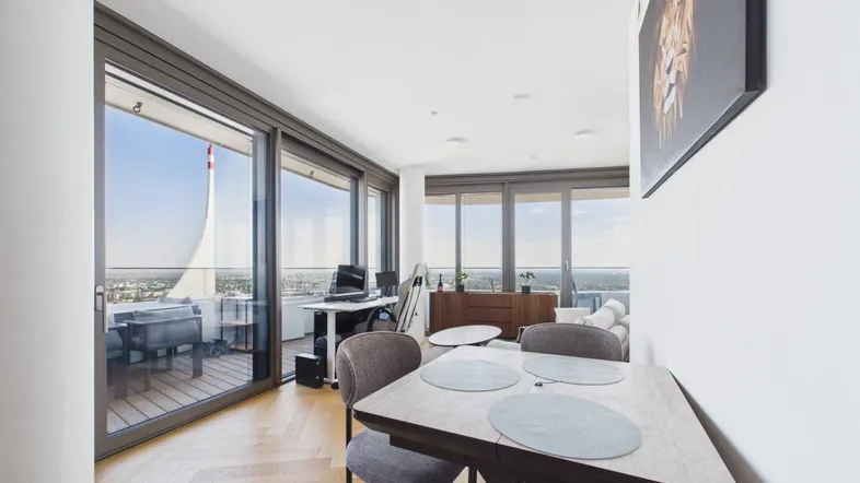 Helles Wohn- und Esszimmer mit Parkettboden, Arbeitsbereich und weitem Stadtblick.