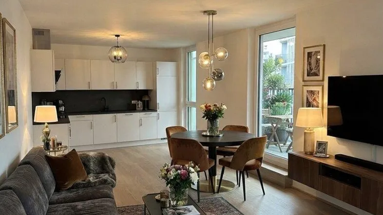 Modern eingerichteter offener Wohn-Essbereich mit integrierter Küche und Zugang zur Terrasse.