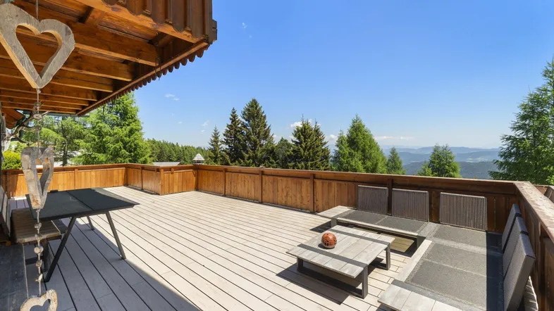 Geräumige Terrasse mit Holzboden, bequemen Loungemöbeln und weitem Bergblick.