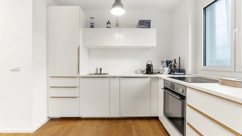 Moderne Einbauküche in Weiß mit Holzakzenten, ausgestattet mit Backofen und Kochfeld.