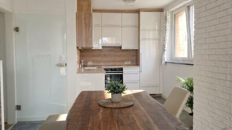 Heller Wohn- und Essbereich mit modernem Holztisch, bequemer Sitzbank und integrierter Küche.