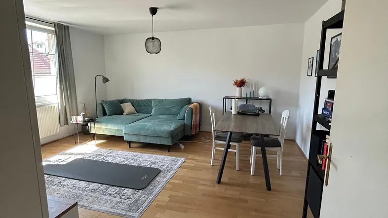 Helles Wohn- und Esszimmer mit Holzboden, Sofa und Esstisch, ideal für geselliges Beisammensein.