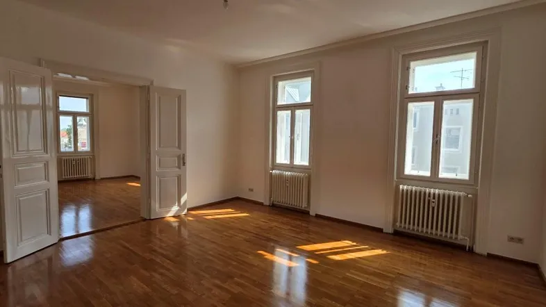 Helles, geräumiges Wohnzimmer mit Holzboden und großen Fenstern, die viel Tageslicht hereinlassen.