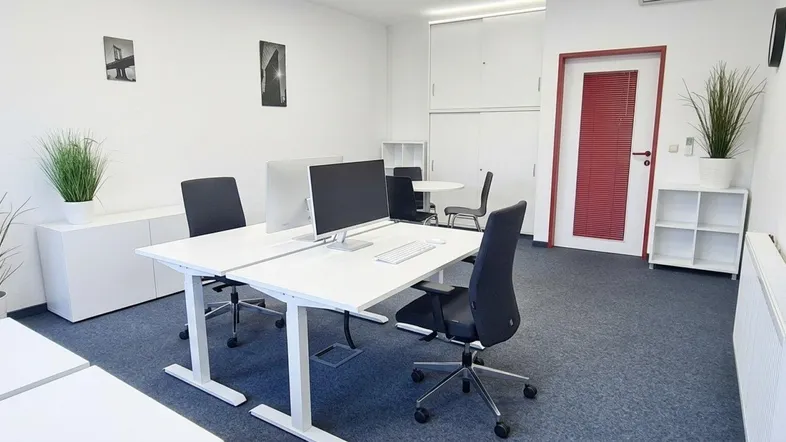 Geräumiges Büro mit zwei Arbeitsplätzen, Teppichboden und schlichter Einrichtung.