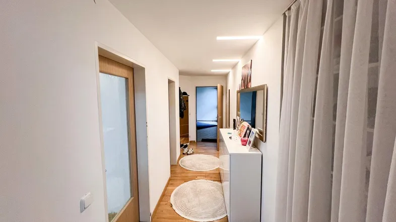 Heller Flur mit Holzfußboden, weißer Kommode und Zugang zu weiteren Räumen.