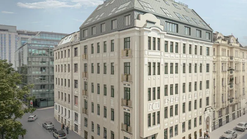 Elegantes Eckgebäude mit klassischer Fassade, Mansarddach und modernen Dachfenstern in einer städtischen Umgebung.