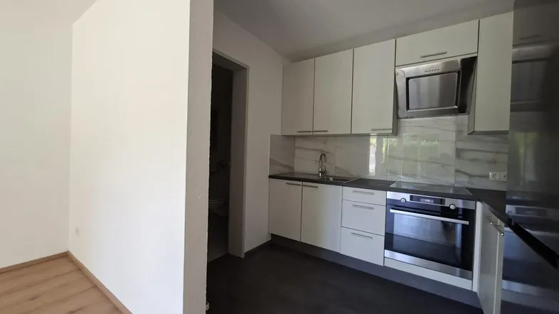 Moderne Küche mit weißen Schränken, dunkler Arbeitsplatte und integrierten Geräten in gutem Zustand.