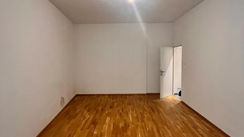 Heller, leerer Raum mit Holzboden und weißen Wänden, bereit zur individuellen Gestaltung.