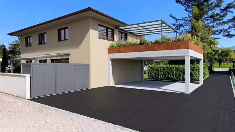 Modernes Haus mit Carport, Zufahrt und gepflegter Außenanlage unter blauem Himmel.