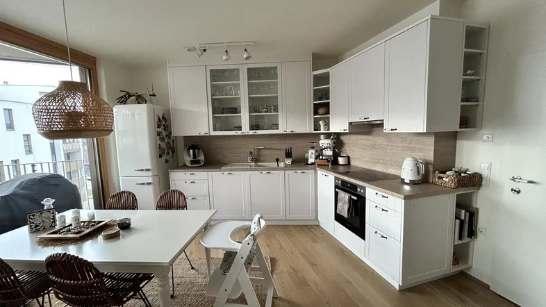 Helle Wohnküche mit weißen Schränken, Holzarbeitsplatten und Zugang zum Balkon.