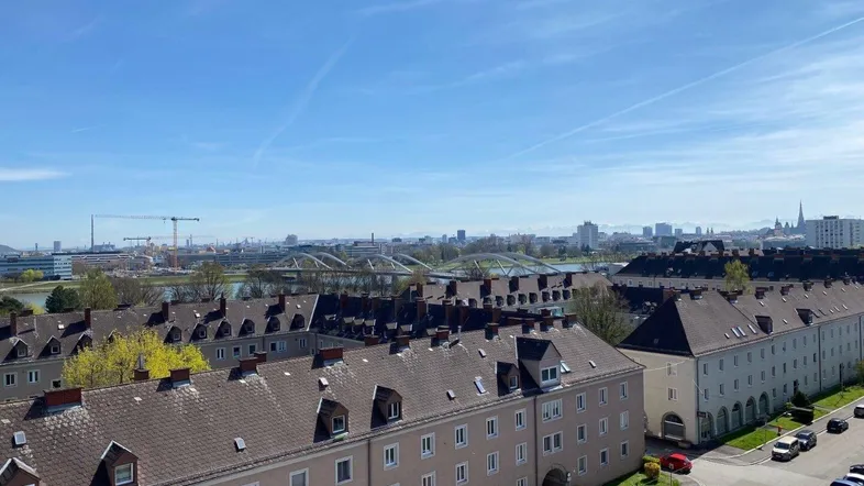 Weitläufiger Blick über die Stadt mit Wohngebäuden und Fluss im Hintergrund unter blauem Himmel.