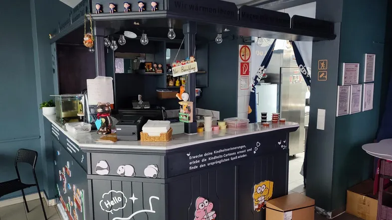 Bunter Thekenbereich mit Cartoon-Dekorationen und Blick auf die Küchenausstattung im Hintergrund.