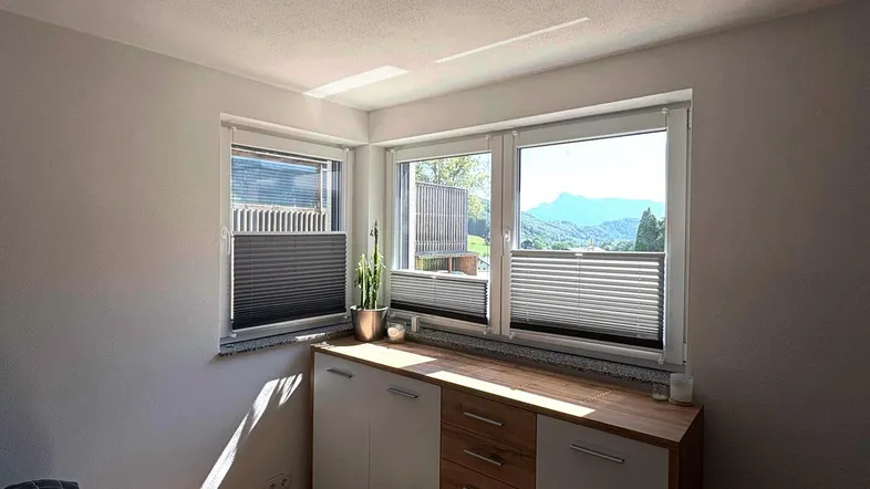 Helles Schlafzimmer mit Holzboden, modernen Möbeln und einem schönen Bergblick durch die Fenster.