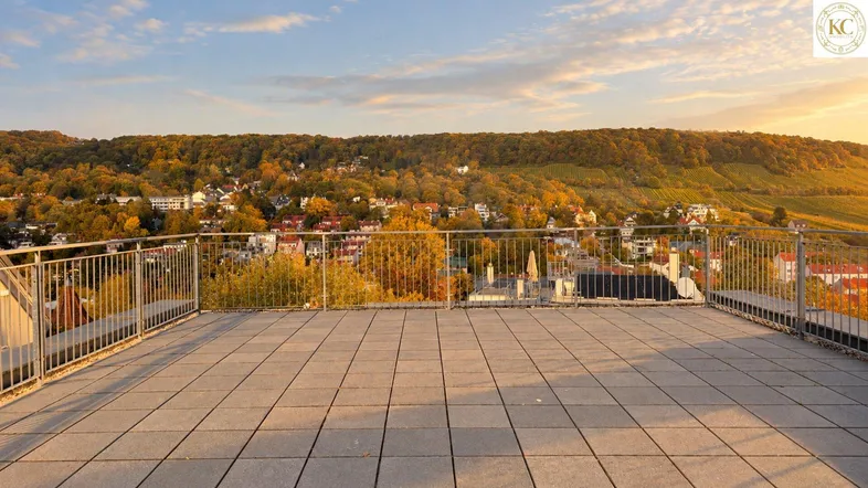 Große Dachterrasse mit weitem Blick über die Stadt, Weinberge und bewaldete Hügel bei Sonnenuntergang.