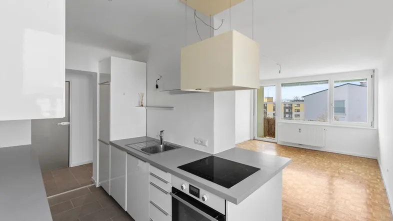 Moderne offene Küche mit Kochinsel, Induktionskochfeld und Blick in den angrenzenden Wohnbereich.