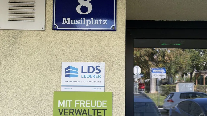 Straßenschild Musilplatz 8 an der Fassade eines Wohngebäudes mit Hinweisen zur Hausverwaltung.