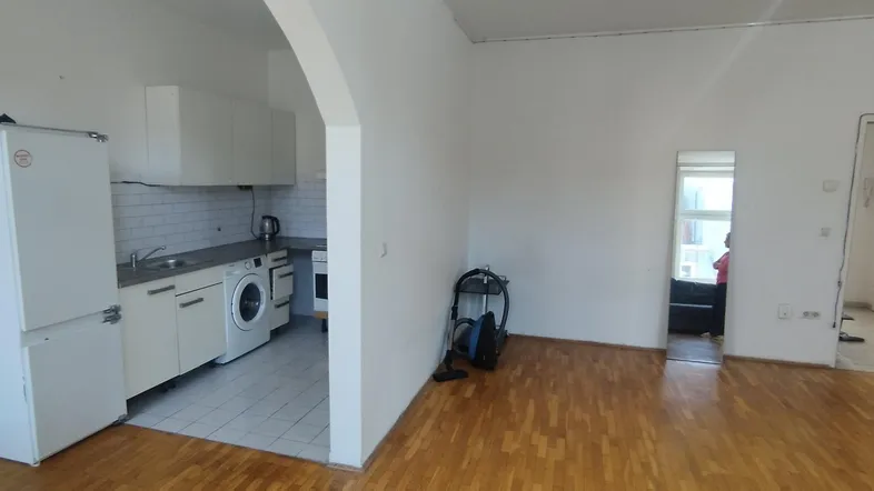 Offener Wohnbereich mit integrierter Küche, weißen Schränken und Holzfußboden.