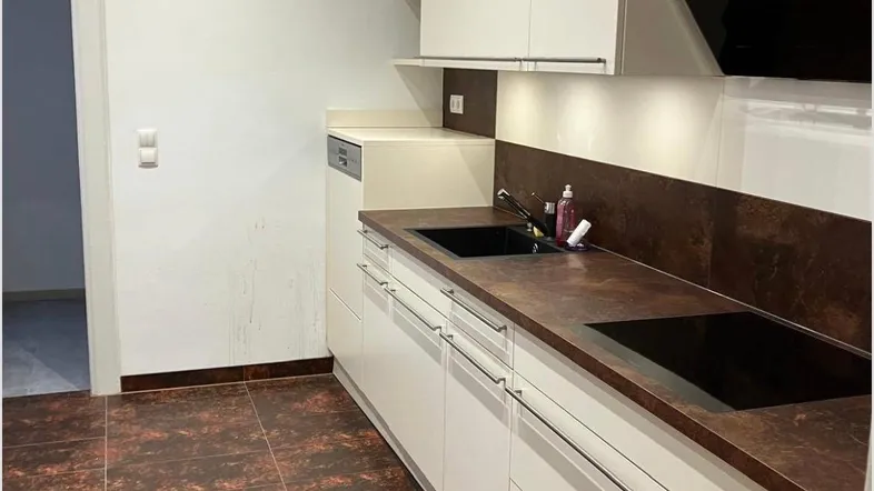 Moderne Küche mit weißen Schränken, dunkler Arbeitsplatte und gemusterten Fliesenboden.