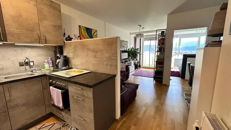Moderne Küche mit Holzoptik-Fronten, integriertem Herd und offener Gestaltung zum Wohnbereich.