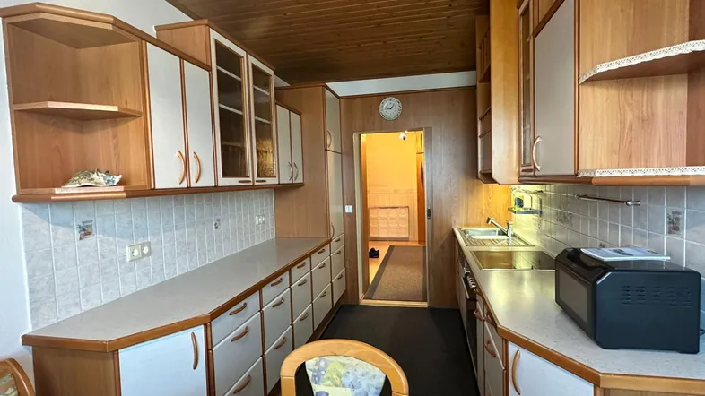 Traditionelle Küche mit Holzdecke, vielen Schränken und einem kleinen Esstisch im Vordergrund.