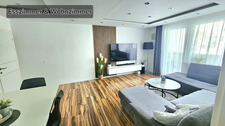 Geräumiger offener Wohn- und Essbereich mit modernem Holzboden und gemütlicher Sitzecke.