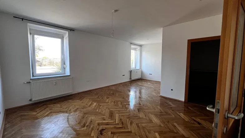 Helles Wohnzimmer mit Fischgrätparkettboden und weißen Wänden, bereit zur individuellen Gestaltung.