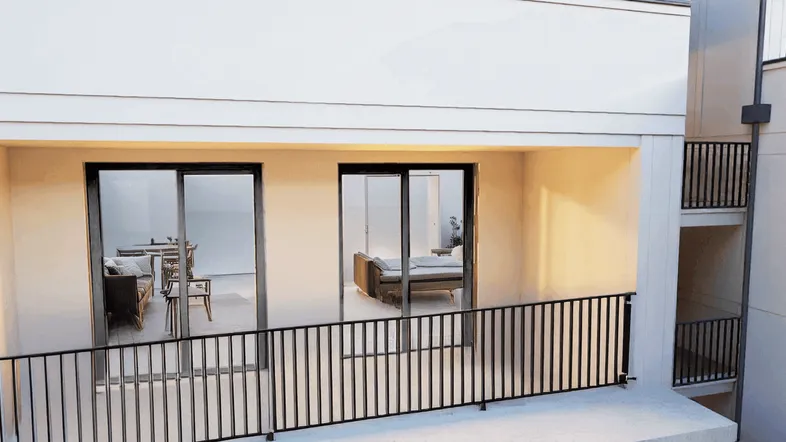 Helle Loggia mit Blick in den Wohnbereich und moderner Balustrade.