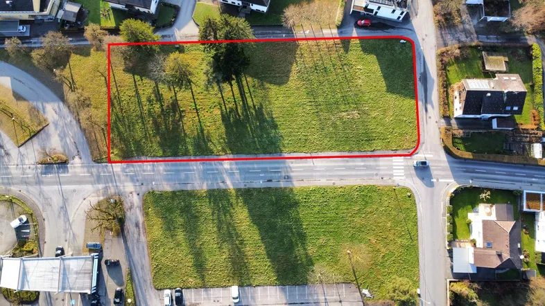 Luftaufnahme eines Grundstücks mit roter Umrandung, umgeben von Straßen und Wohngebäuden.