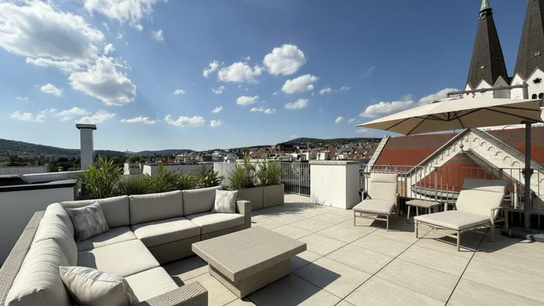 Geräumige Dachterrasse mit bequemen Loungemöbeln, Sonnenschirm und weitem Blick über die Stadt.