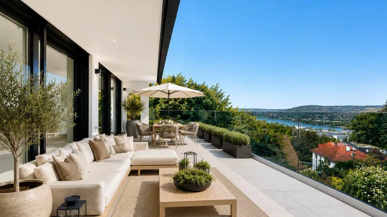 Große, modern eingerichtete Terrasse mit bequemen Loungemöbeln und weitem Blick auf die Landschaft und den Fluss.